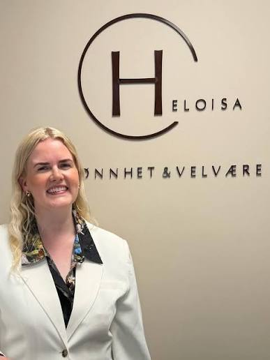 Heloisa foran logoen i klinikken